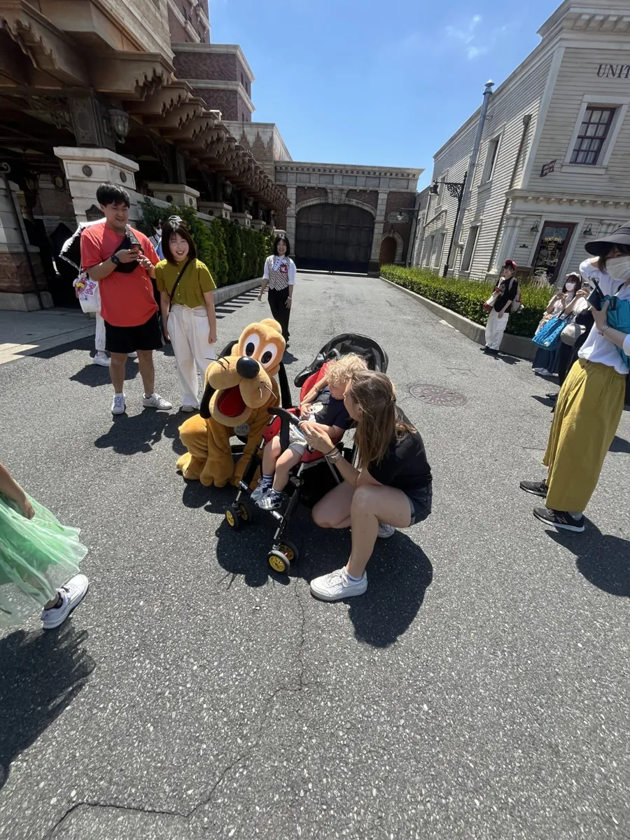 Our toddler in a rented stroller at Tokyo DisneySea, with a parent beside him